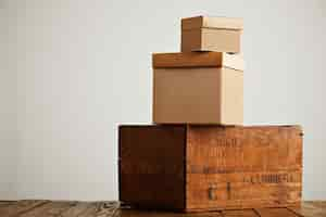 Free photo brown boxes of different sizes and textures arranged in a pyramid on top of a rustic wooden table isolated on white