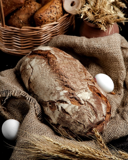 Буханка черного хлеба подается на льняной ткани в деревенском стиле