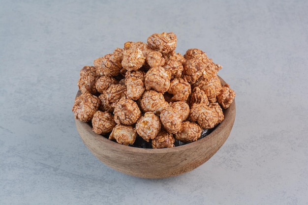 Brown candy coated popcorn in a bowl on marble surface