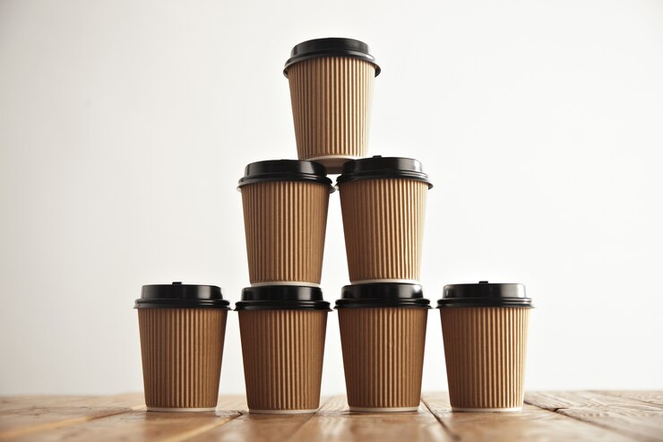 Free Photo brown cardboard take away paper cups with black caps in pyramid house shape on rustic vintage table in center of picture