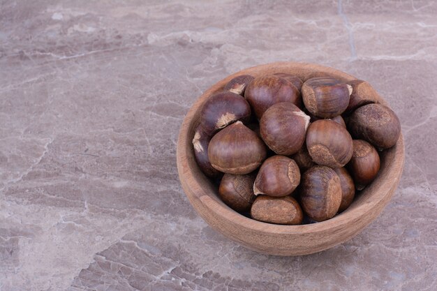 Foto gratuita castagne marroni in una tazza di legno sulla pietra