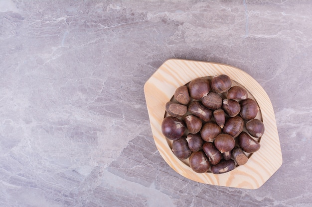 Brown chestnuts in a wooden platter on the stone