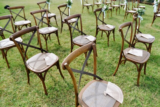 Brown chiavari chairs and hand fans outdoors on the grass