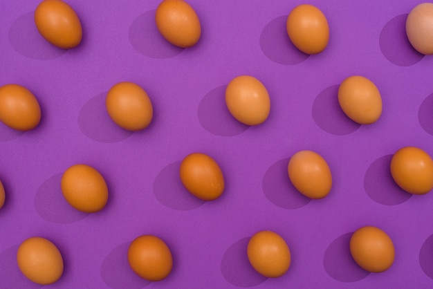 Free photo brown chicken eggs scattered on purple table