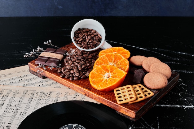 Free photo brown coffee beans with orange slices and cookies