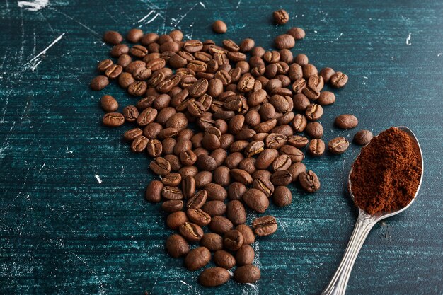 Brown coffee beans with a spoon of powder.