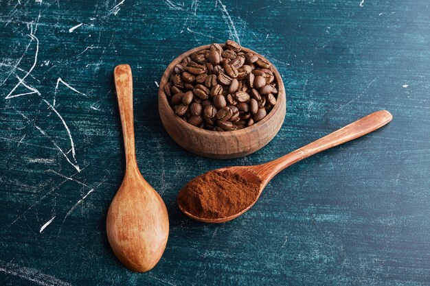 Brown coffee beans in wooden cup and spoons.