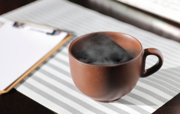 Коричневая чашка кофе с горячим паром на рабочем столе