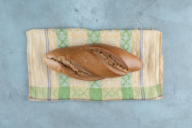 Коричневый вкусный хлеб на красочной скатерти.