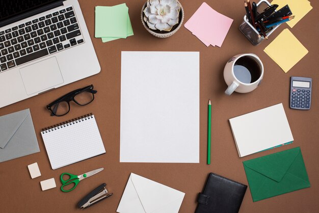 Brown desktop with coffee cup; laptop and office supplies