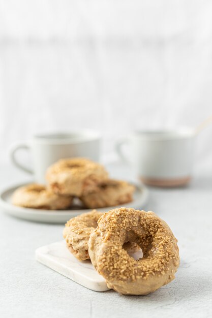 Brown doughnut beside white ceramic mug on white table