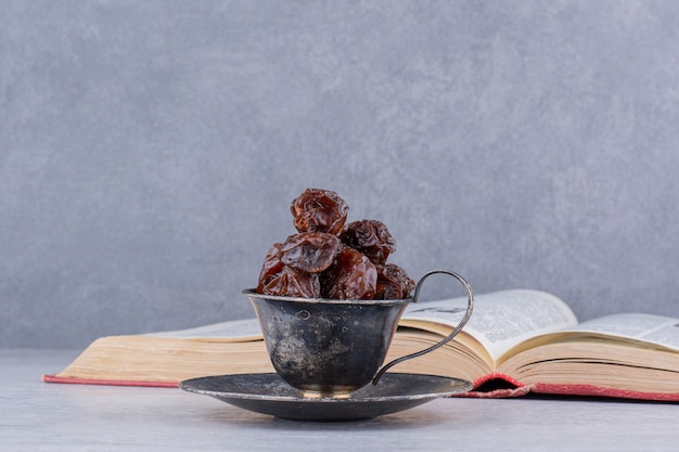 Brown dried cherries inside a dish on concrete surface