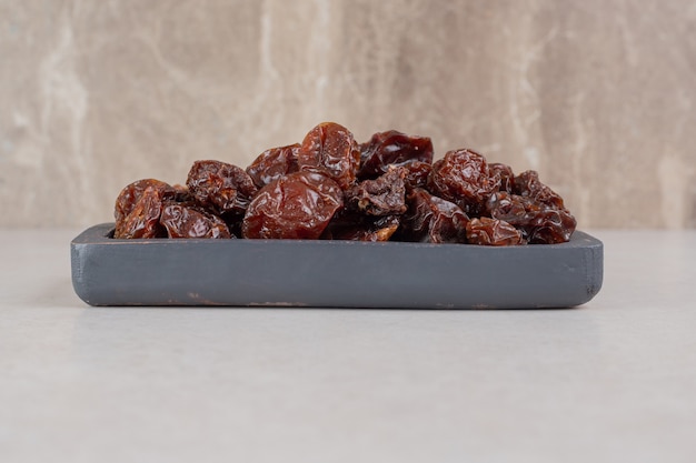 Brown dried cherries on a wooden platter