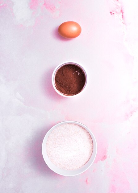 갈색 계란; 코코아 가루와 분홍색 질감 된 배경 위에 밀가루에 그릇