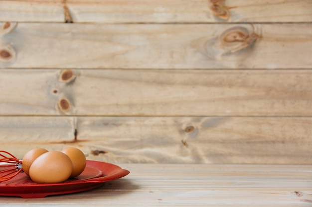 Free photo brown eggs with whisk on plate