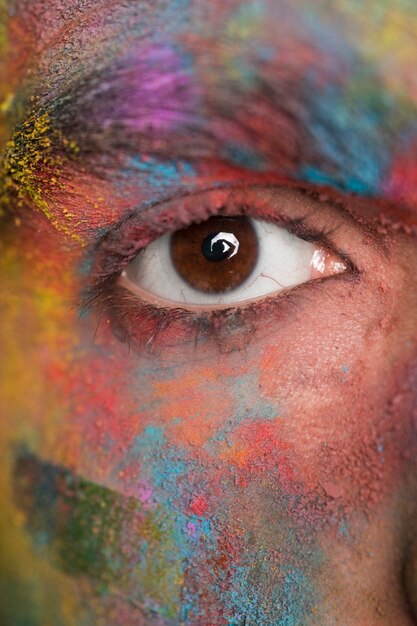 Brown eye of young man with bright colorful paint