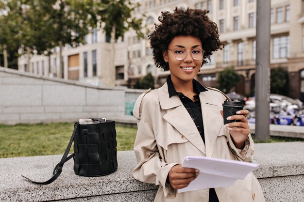 Brown-eyed charming brunette woman holds coffee cup