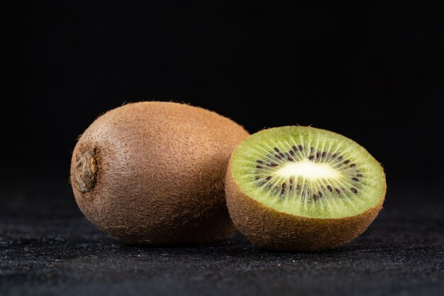 Brown kiwi fresh juicy mellow half cut isolated on dark