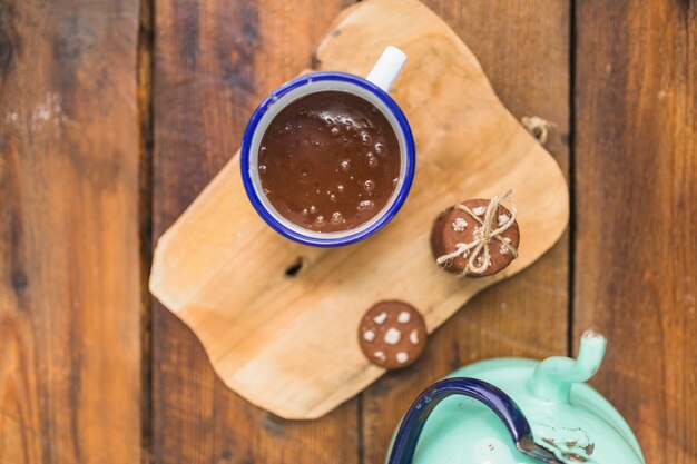 Brown liquid in cup near biscuits and kettle