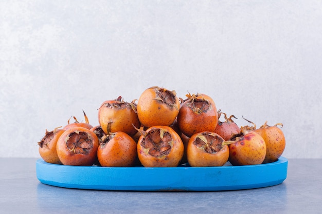 Foto gratuita nespole marroni in un piatto blu su superficie grigia