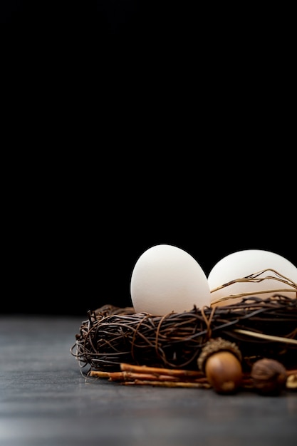 Бесплатное фото Коричневое гнездо с белыми яйцами на черном фоне