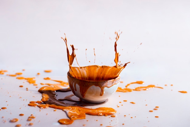 Free photo brown paint splash and cup abstract background