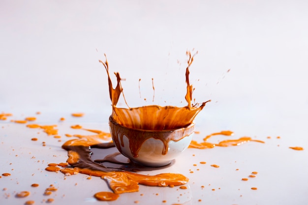 茶色の塗料スプラッシュとカップの抽象的な背景