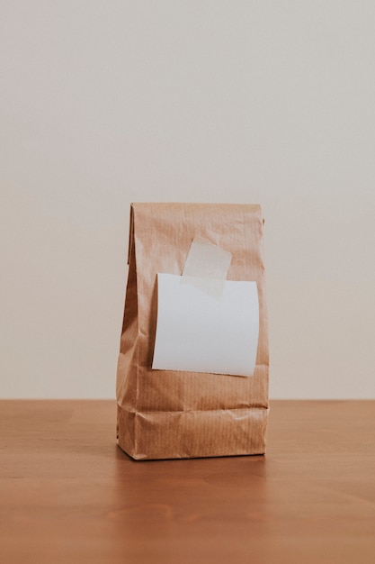 Free photo brown paper bag with a blank white notepaper