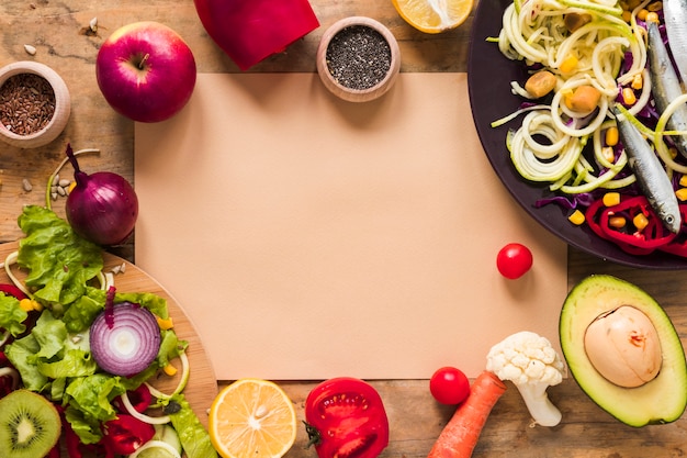 건강한 다진 야채로 둘러싸인 갈색 종이; 과일; 테이블에 재료