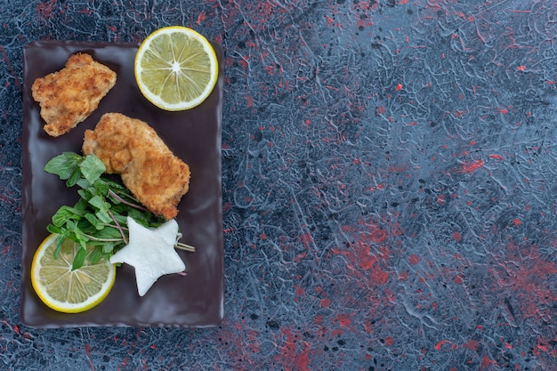 ミントとレモンのスライスが入った鶏肉の茶色のプレート。