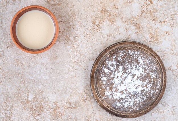 A brown plate of flour and a clay bowl