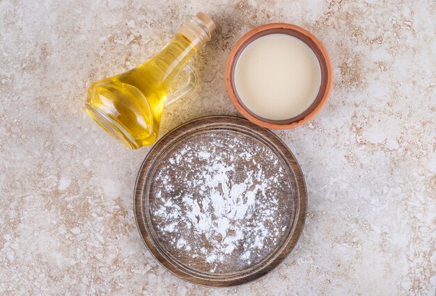 A brown plate of flour and a glass cup of milk