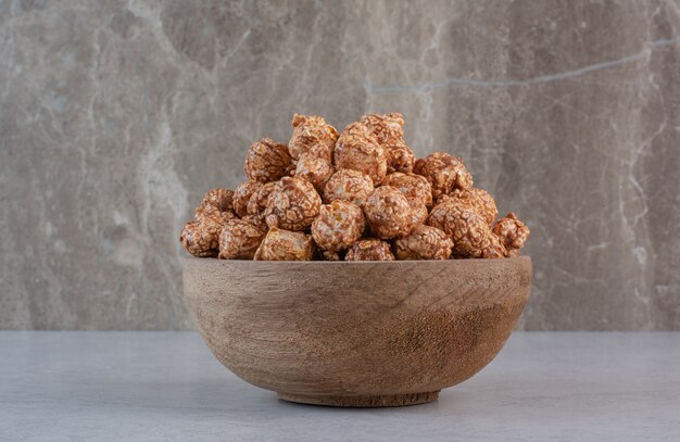 Brown popcorn candy piled in a small bowl on marble.