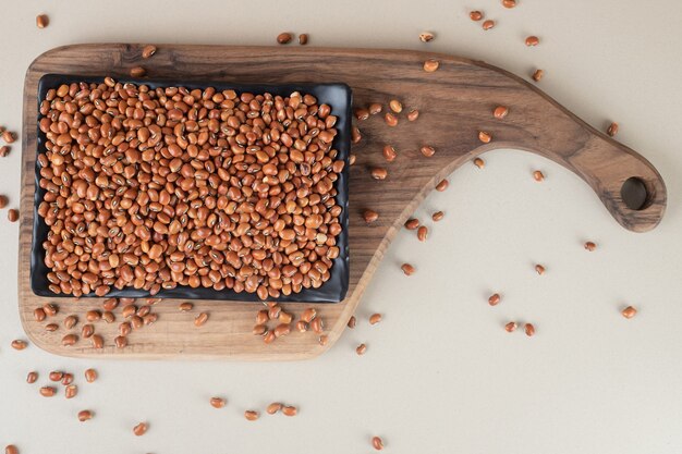 Brown raw beans in a platter on concrete.