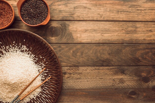 Brown; red; and white rice grains on wooden table