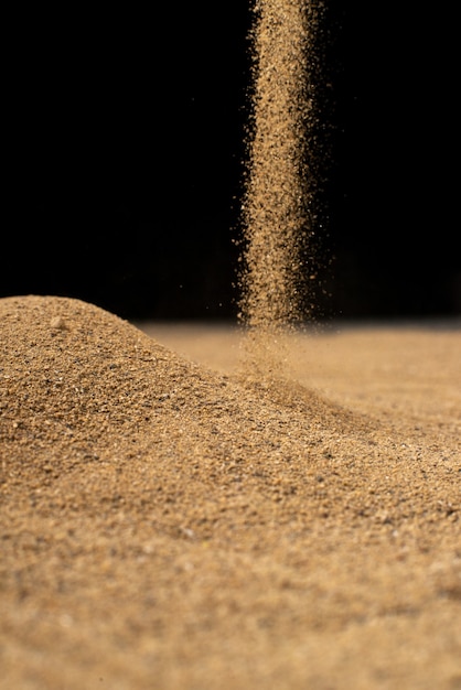 Free photo brown sand falling on black wall