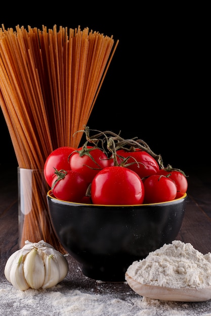 Бесплатное фото Коричневая спагетти и томатно-чесночная мука на черной поверхности