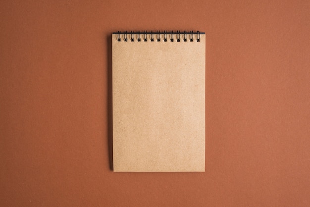 Brown spiral notepad on colored background