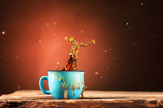 Brown splashes out drink from cup of tea on a brown background