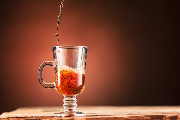 Foto gratuita brown spruzza la bevanda dalla tazza di tè su una parete marrone