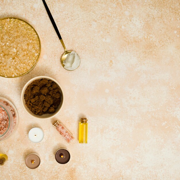 Brown sugar; coffee powder; himalayan pink salt and essential oil with candles on textured backdrop