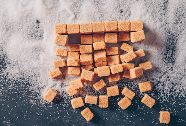 Brown sugar on a sugar powder and dark table. flat lay.