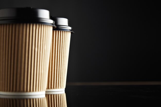 Brown take away paper cups closed with caps isolated on left