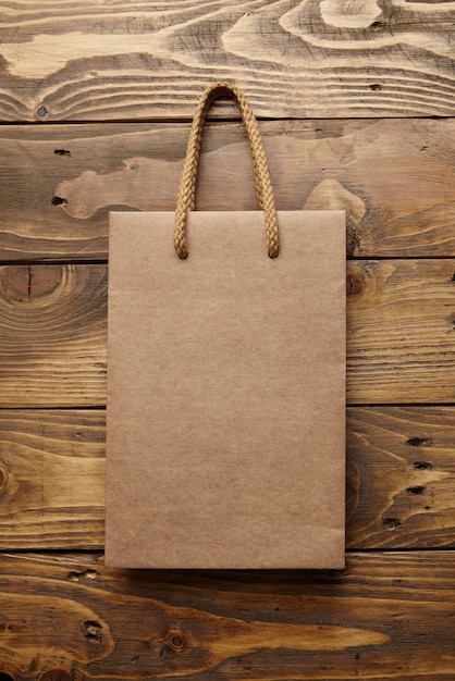 Brown takeaway bag from thic recycled craft paper on rustic wooden table 