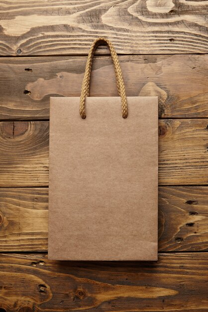 Brown takeaway bag from thic recycled craft paper on rustic wooden table 