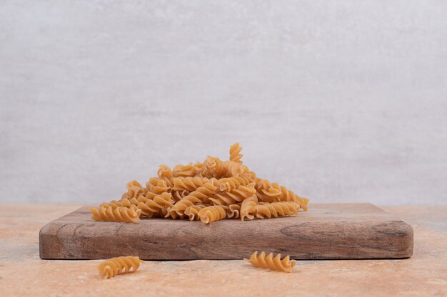 Brown uncooked spiral macaroni on wooden board. High quality photo