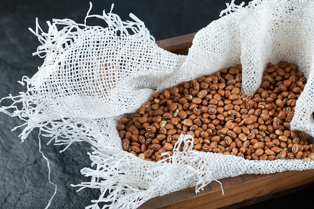 Brown unprepared kidney beans on a wooden basket