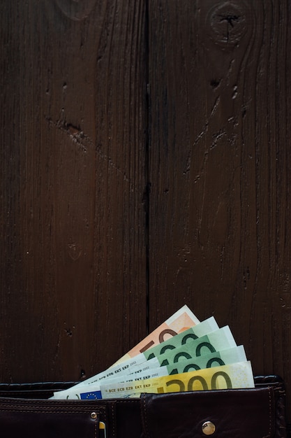 Free photo brown wallet with euro banknotes on wooden table