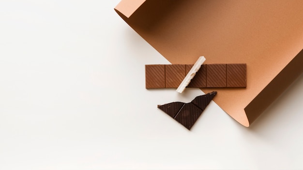 Brown; white and dark chocolate bar on card paper against white backdrop