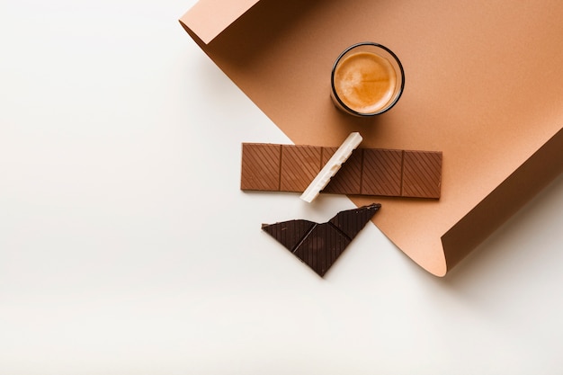 Brown; white and dark chocolate bar with coffee glass on paper against white backdrop